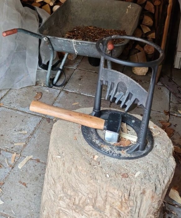 Vedklyvning stubbe med yxa och träblock, skottkärra i bakgrunden, placering i garage eller skjul.