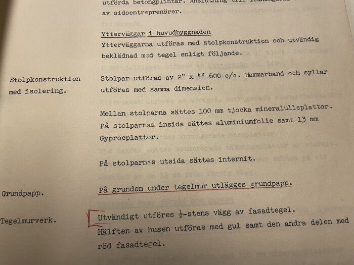 Byggbeskrivning från 1958 med detaljer om stolpkonstruktion, mineralullsisolering och tegelfasad, med understrykningar av viktiga delar.