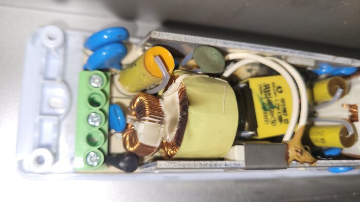 Elektronisk krets med kondensatorer, spolar och kopplingar, inuti ett metallhölje.