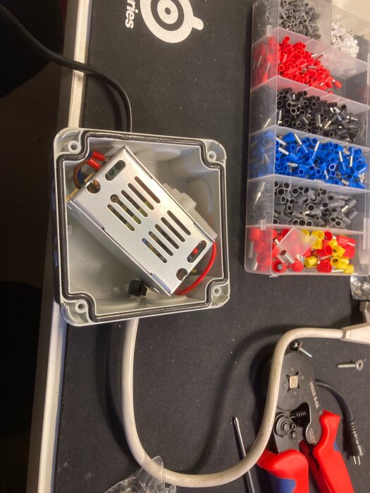 Elektronisk transformator monterad i kopplingsdosa med verktyg och kabelskor runtom, redo för installation i byggprojekt.
