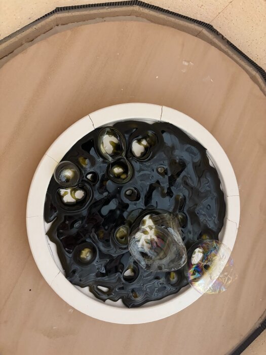 Glaset i formen visar bubblor och ojämn yta från experimentet med smältning vid hög temperatur för att skapa en lampa.