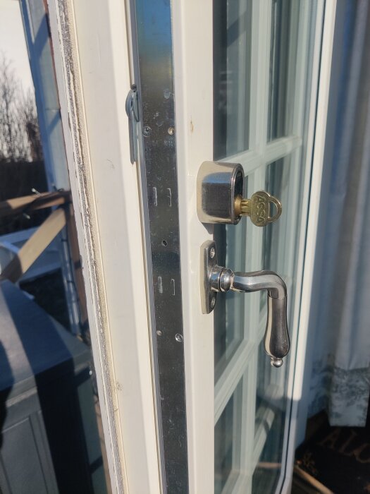 Altandörr med spanjolett och handtag invändigt, saknar handtag utvändigt. En nyckel är insatt i låset med modell 1049F.