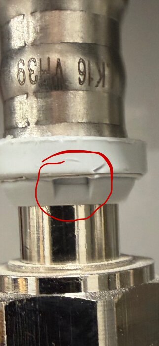Närbild av en koppling med en vit slang i en slits, inringad med rött, som visar korrekt installation enligt instruktionerna.