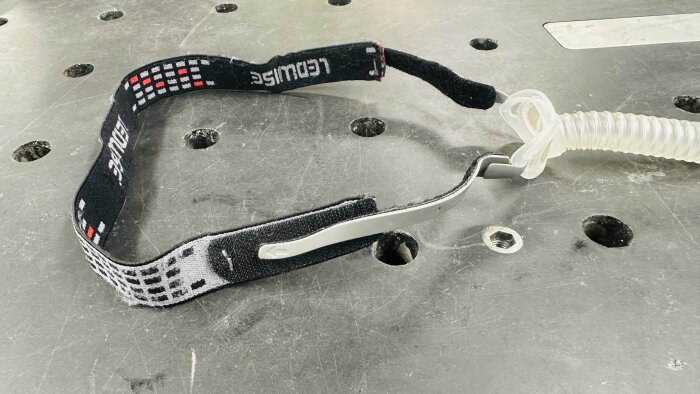 Hemgjord CPAP-maskrem med kardborreband och elastiskt spännband, uppgraderad för bättre passform och komfort, ligger på ett arbetsbord.
