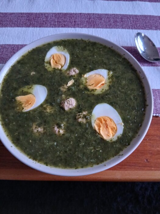 Grönkålssoppa med frikadeller och ägghalvor i en vit skål.