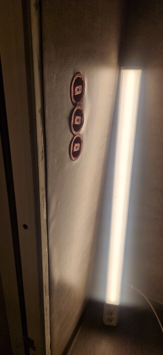 Badrumsvägg med tre oskyddade eluttag, bredvid ett lysrör som lyser starkt.