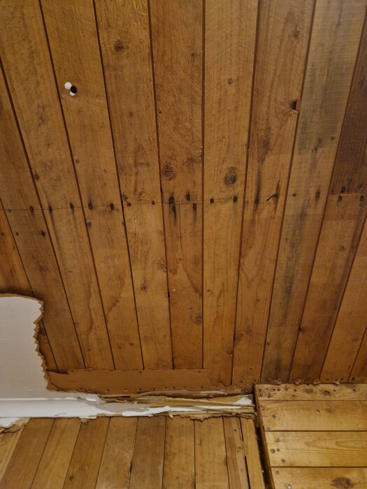 Trävärv med skadad yta och trasig tapet längst ner, något renoveringsbehov.