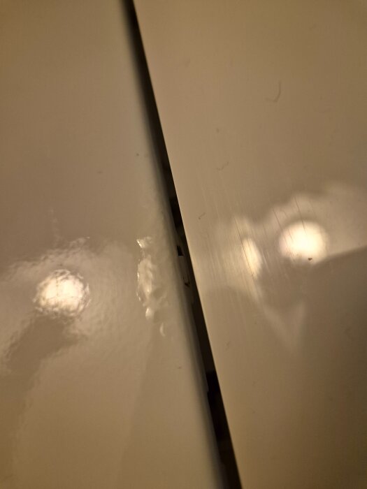 Närbild på ett tvättmaskinslock med rostbubblor under lacken, vilket kan indikera fuktskador.
