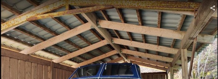 Trätak med plåtbeläggning och rostiga stålbalkar under en carport där en båt är parkerad.