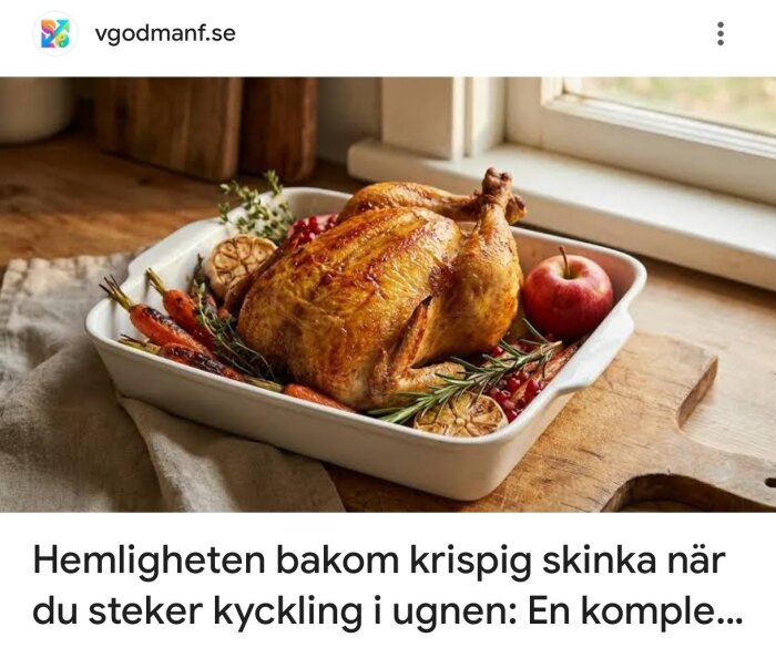 Stekt kyckling med krispigt skinn i en ugnsform, omgiven av morötter, örter, vitlök och ett äpple, på ett träbord vid ett fönster.