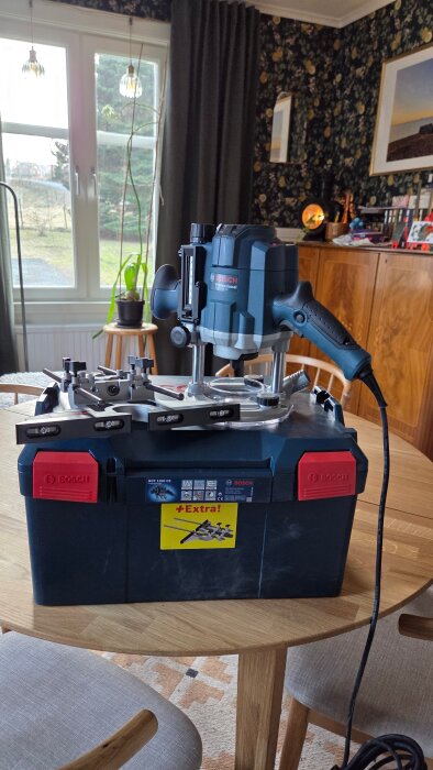 En Bosch GOF fräs står på ett bord, omgiven av moderna möbler och stora fönster.