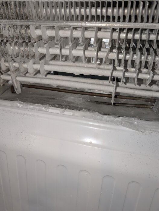 Isblock vid avrinningshålet i frysen på en LG kombinerad kyl/frys, med synliga frostbelagda rör och komponenter inuti frysdelen.