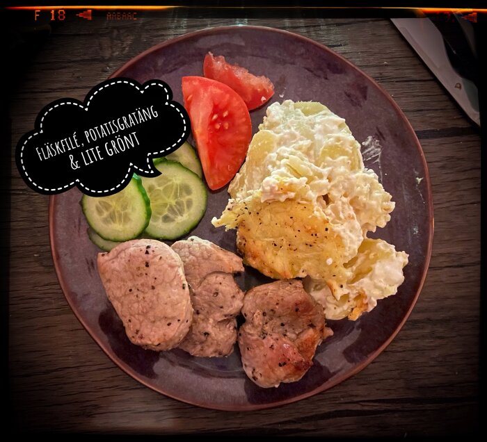 Tallrik med fläskfilé, potatisgratäng, gurkskivor och tomatklyftor. Text på bilden: "Fläskfilé, potatisgratäng & lite grönt".