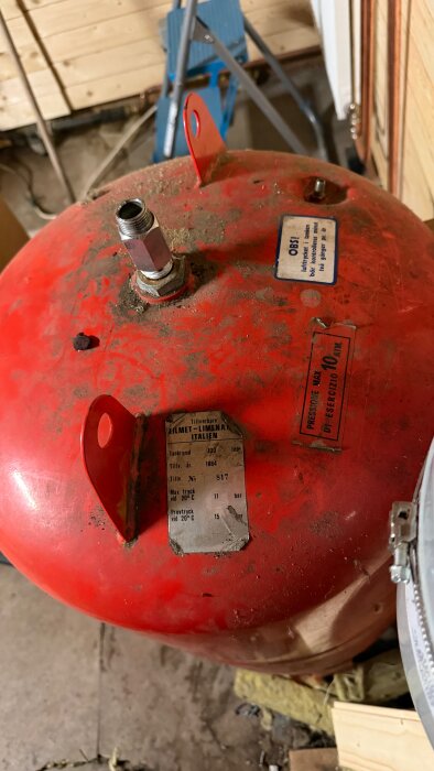 Röd Zilmet-hydropress i närbild med tryck- och kapacitetsetiketter, installerad i ett träklätt rum, del av diskussion om högt tryck och pumpdilemma.
