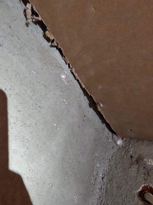 Ojämna gipsskivor och mellanrum mot en betongvägg i ett källarrum, visar en utmaning vid byggprojekt.