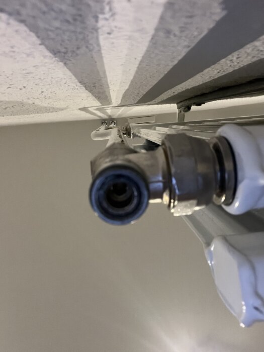 Närbild på en del av ett elementrör med en ventil kopplad till en radiator.