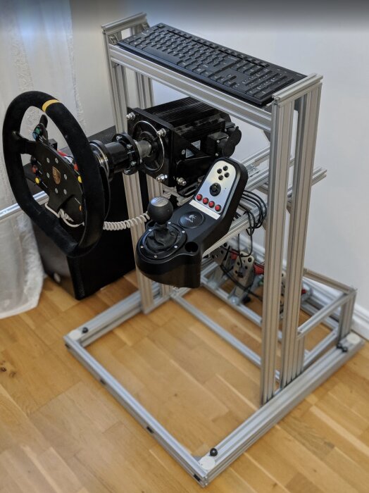Fällbar aluminiumrigg för simracing med ratt, växelspak och pedaler monterade på träram.