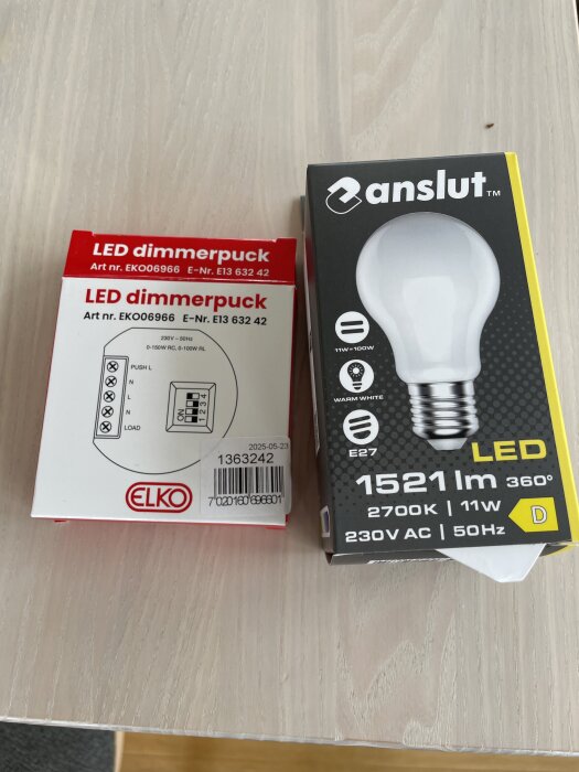 Förpackning av ELKO LED dimmerpuck och Anslut LED-lampa på ett bord.