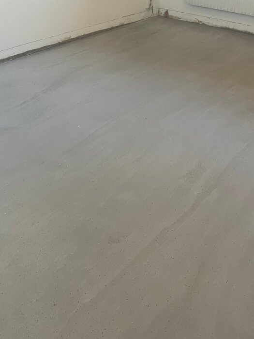 Betonggolv i ett källarrum som nyligen fått laminatgolvet borttaget, med synlig färgförändring och potentiella luktproblem.