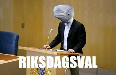 Man i kostym med delfinhuvud står vid talarstol i riksdagen, texten "RIKSDAGSVAL" syns nedtill.