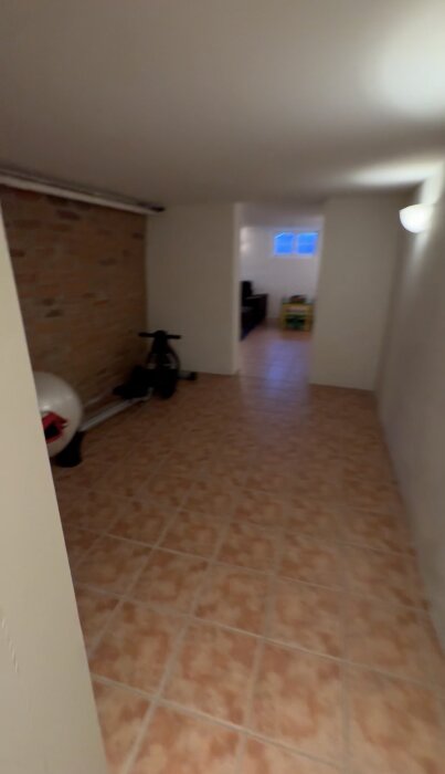 Källarkorridor med tegelvägg, klinkergolv och en träningscykel; plan för vinväggsprojekt.