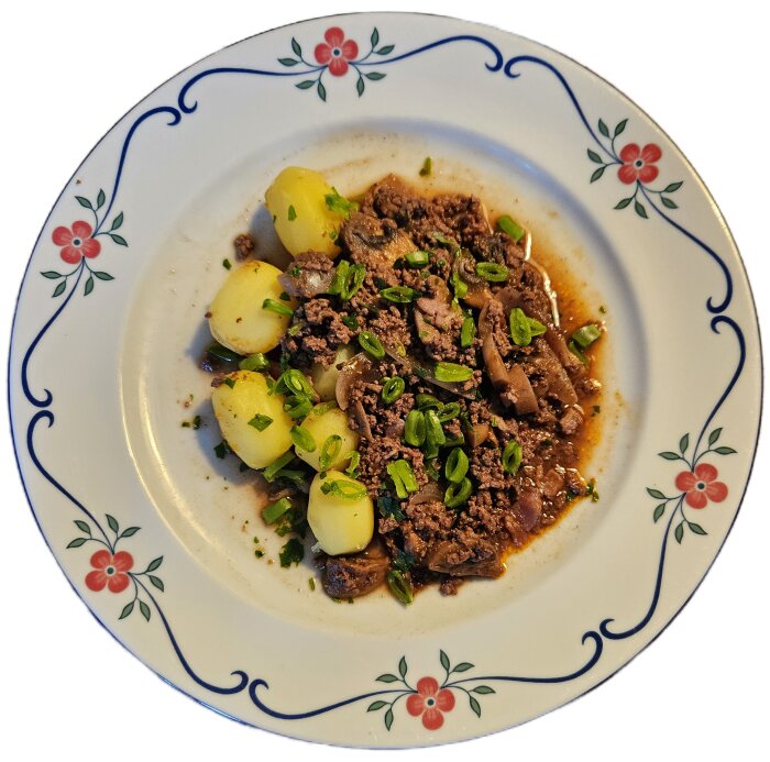 Tallrik med "falsk" Boeuf bourguignon av högrevfärs, klyftad rödlök, serverad med potatis, grönsaker och toppad med färska örter.
