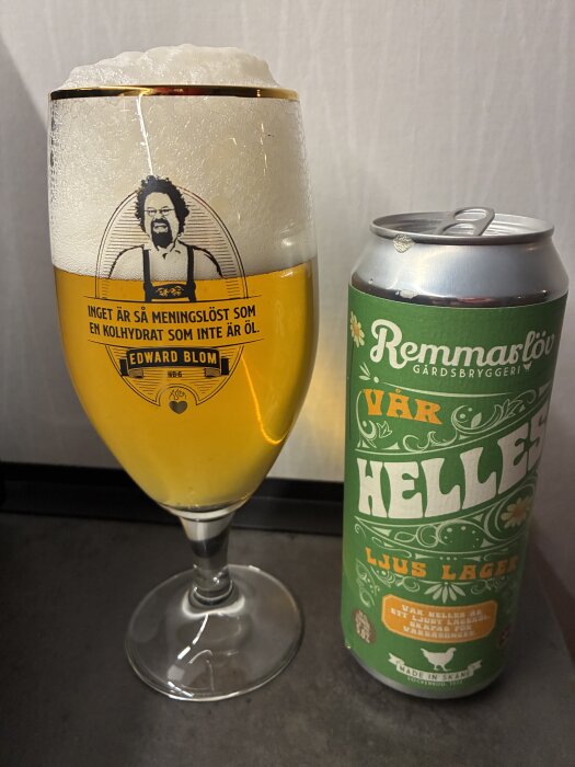 Glas med skummande öl från Remmarlöv gårdsbryggeri bredvid en burk Märkets Vår Helles ljus lager.