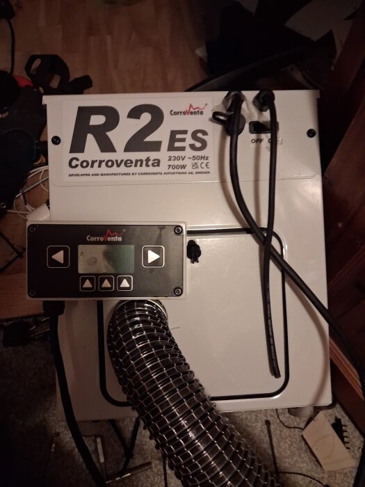 Avfuktningsenhet Corroventa R2 ES med sladdar och kontrollpanel, placerad på golvet i ett ombyggnadsområde.