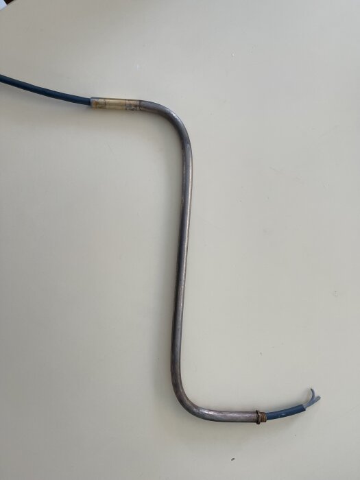 Gråaktigt, lätt rostigt rör med böjd form och blå kabel syns; diskussion om eventuell mässingsplätering och rengöring av en golvlampa.
