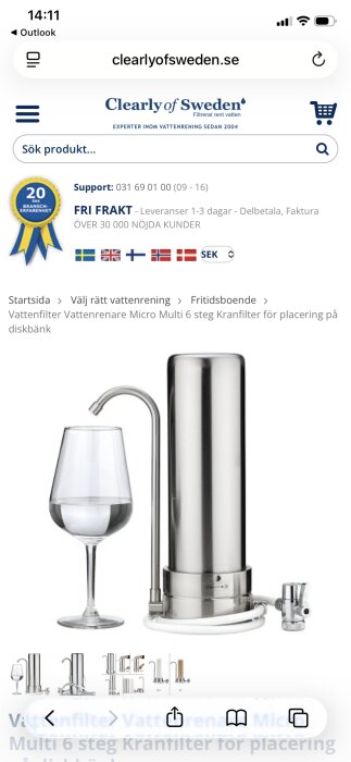 Vattenfilter på diskbänken i rostfritt stål med koppling till kranen och ett glas fyllt med vatten.