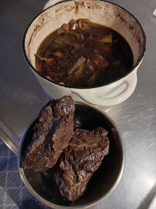 Oxkinder efter sju timmars långkok, serverade på ett fat med gryta i bakgrunden.