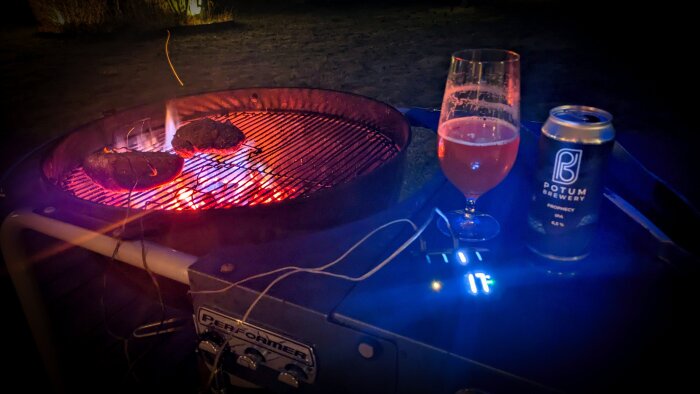 Grill med två köttbitar på het glöd samt ett glas och en burk Potum Prophecy-öl bredvid, redo för indirekt grillning.