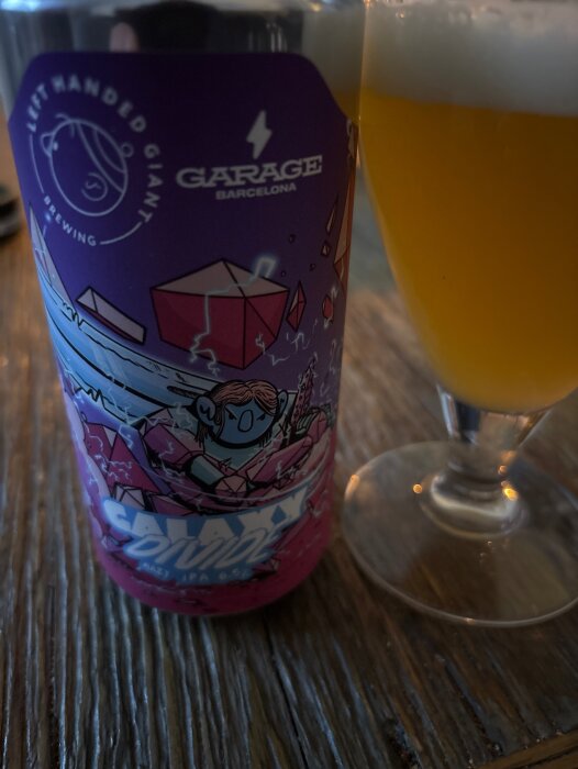 Burk av ölet Galaxy Divide, 6,5% Ipa från Left Handed Giant Brewing, placerad bredvid ett glas med skummande öl.