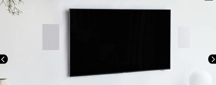 TV med två inbyggda högtalare på en vit vägg i ett vardagsrum.