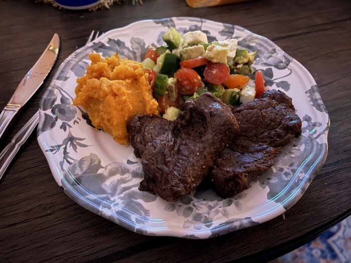 Entrecote, sallad med fetaost och avokado, sötpotatismos och sås på en tallrik.