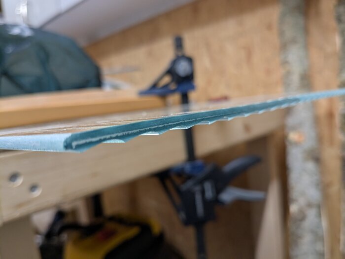 Slipad kant av tunn trä- eller laminerad skiva inspänd i verkstad.