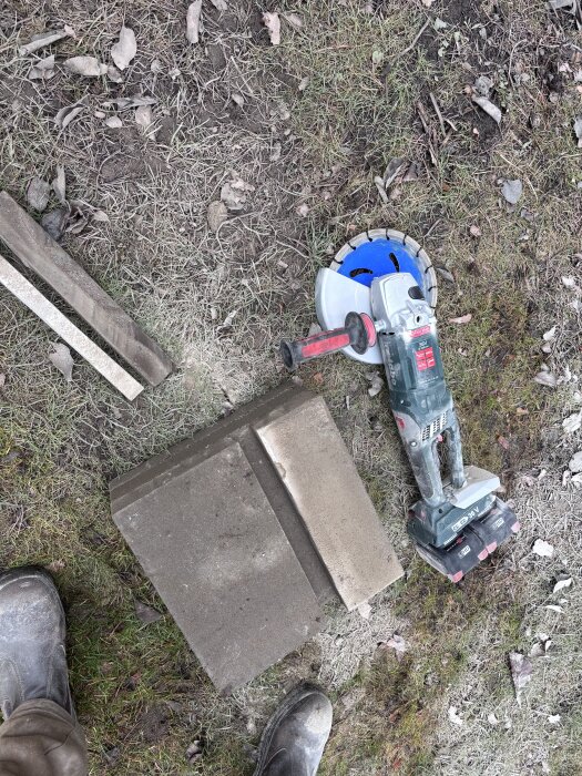 Batteridriven vinkelslip och marksten på gräsig mark, används för att uppdatera kaninburens säkerhet med ca 15 snitt.