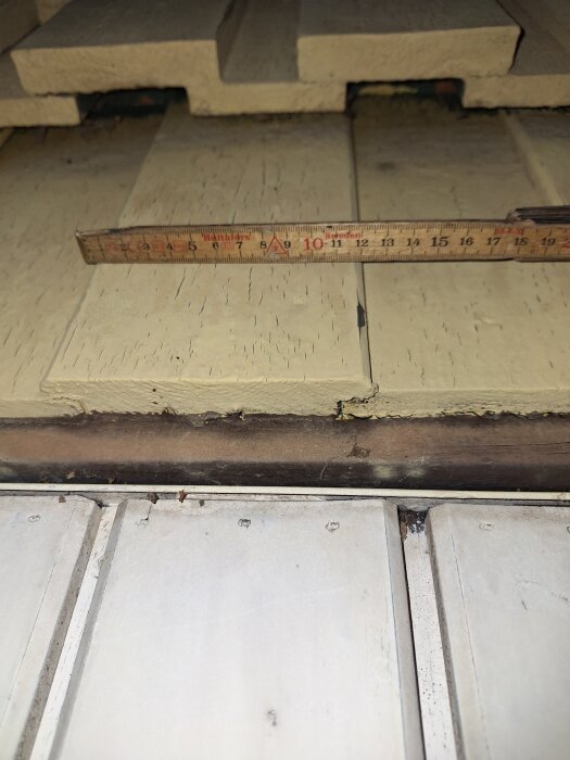 Närbild på beige ytterpanel med en tumstock ovanpå, som mäter ungefär 16 cm i bredd.
