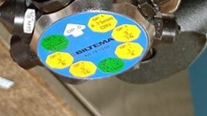 En blå och gul skala med olika dimensioner och text "BILTEMA" på en metallventil.