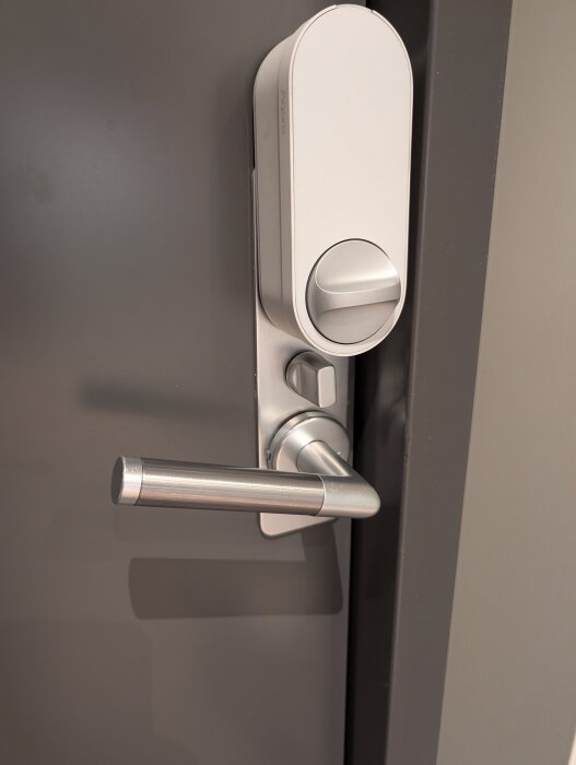 Dörr med Aqara smartlås installerat ovanför traditionellt dörrhandtag, visar enkel integration av smart teknik i befintligt låssystem.