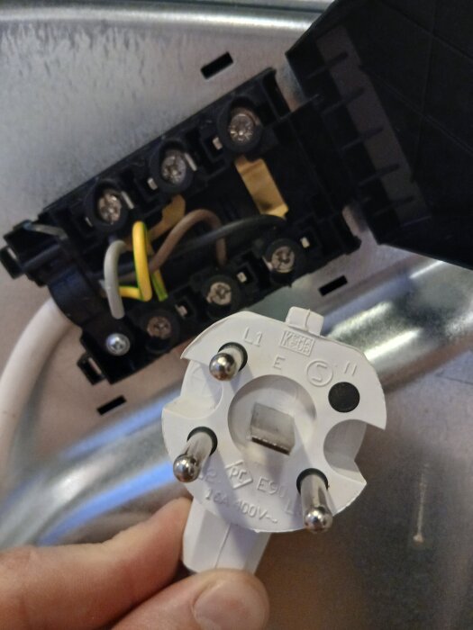 Elektrisk installationskontakt med anslutningsschemat L1, L2, L3 och jord vid en induktionshäll. Trådarna är kopplade till en dosa.