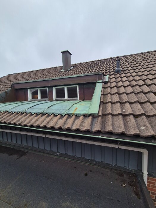 Tegeltak med skorsten och takfönster, plåt runt fönsterkupan, synlig hängränna, Göteborg.