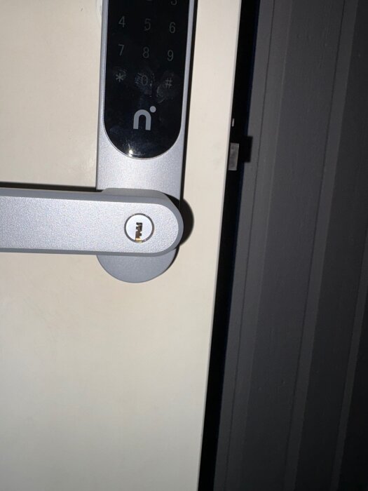 Elektroniskt dörrlås på en dörr med synlig tryckknappspanel och nyckelhål, där låset uppvisar installationsproblem enligt inlägget.