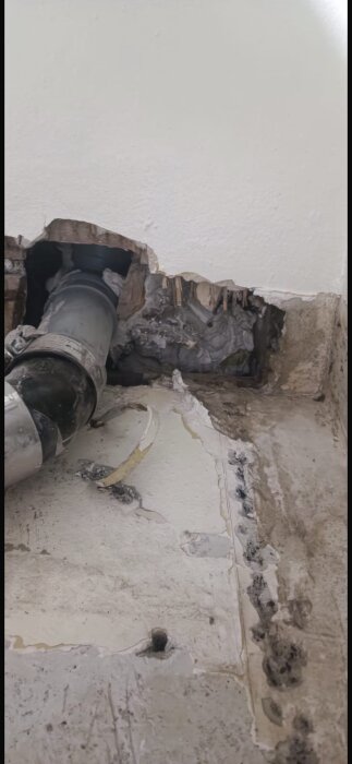Bilden visar ett öppnat tak med blottad avloppsstam och igenmurad ventilation i en pågående badrumsrenovering.