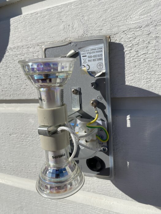 GU10-lampa monterad på vägg med synliga skruvar och kablar; hölje borttaget för lampbyte.