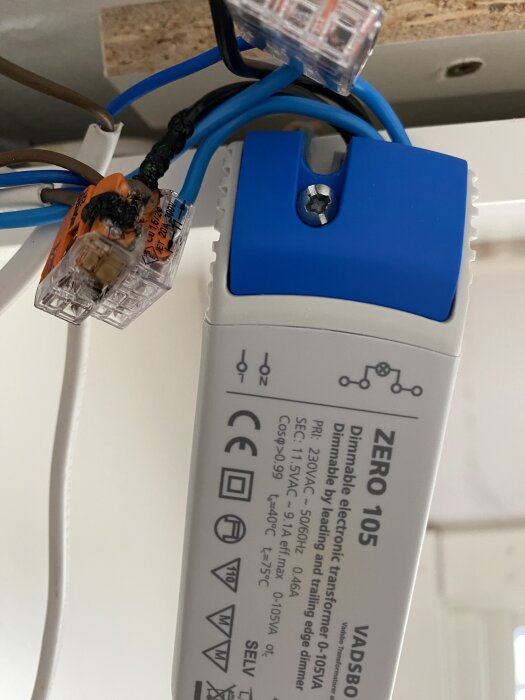 Smält Wago-koppling och kablar bredvid en dimmer för halogenspots, visar möjliga elektriska problem i anslutningen.
