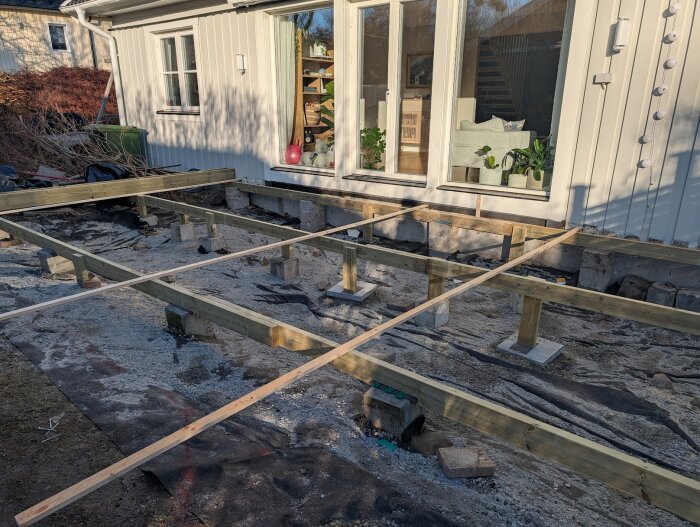 Ramverket för en altan under byggnation, där en tvärliggare i mitten endast är fastskruvad i små uppstickande plankbitar.