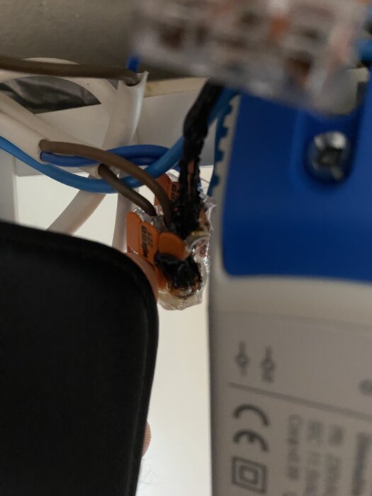 Smält plastlock och smält fast kopplingsklämma med kablar i elektrisk installation.