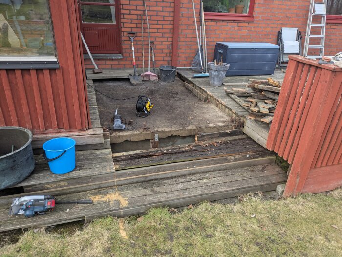 Riven altan med verktyg och material i närheten, visar pågående renoveringsarbete vid ett tegelhus.