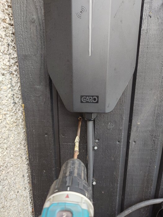 Borrmaskin används för att montera en Garo-laddbox på en trävägg.